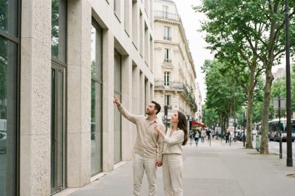 Couple visitant un immeuble neuf dans le 12e arrondissement de Paris, façade contemporaine en pierre et verre, ambiance urbaine parisienne